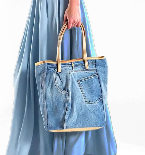 תיק ג'ינס בהיר עם ידיות עור, מעוצב לבישוי יומיומי, בסגנון מודרני ואלגנטי.