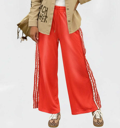 טרנינג בגוון אורנג' עם פסי תחרה, מכנסיים רחבים לנוחות ואסתטיקה ספורטיבית ואלגנטית.