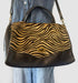 Italian leather and fur handbag in leopard and black with copper accents, stylish shoulder strap, and chic design.