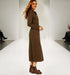 שמלה מכופתרת, בגוון חום, עם שרוולים ארוכים, מוצגת על דוגמנית בתצוגת אופנה.