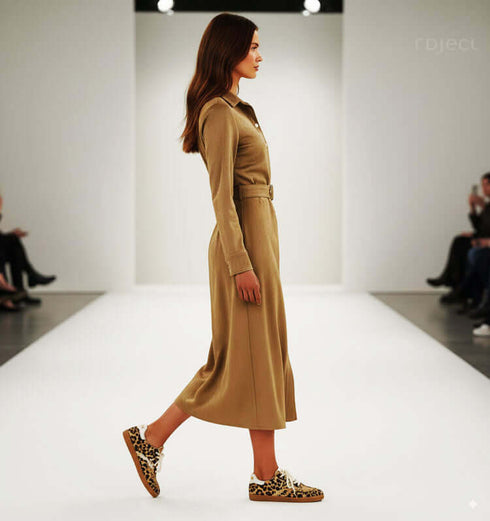 שמלה מכופתרת מבד דמוי ז'אמש בגוון בז', עם נעליים בעלות הדפס נמר, על מסלול אופנה.