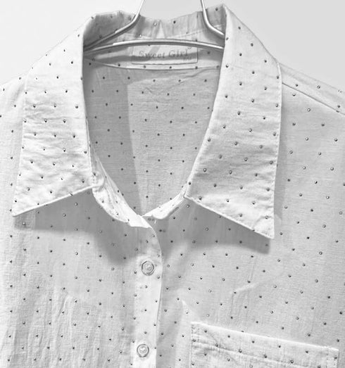 Close-up of a white button-up shirt with small black polka dots, showcasing the collar and details.