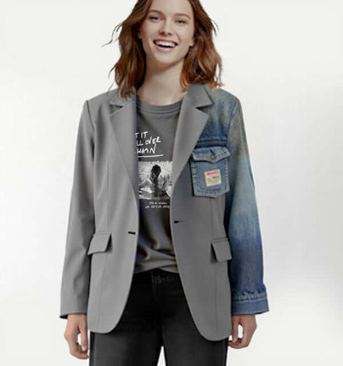 אישה מחייכת בשמלת ג'קט אלגנט אפור עם שרוול ג'ינס, סגנון מודרני וייחודי.