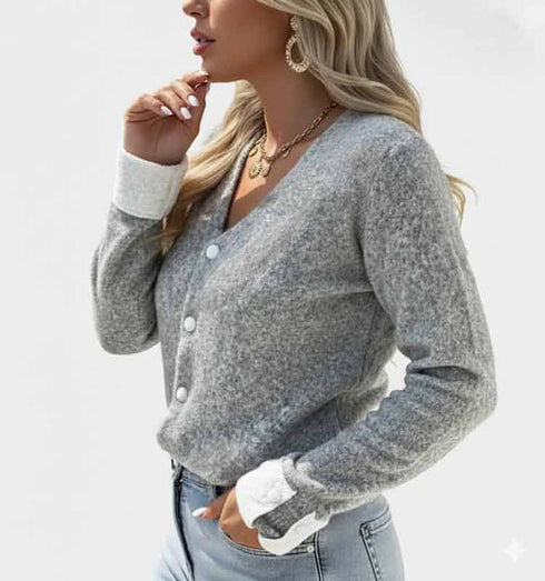 קרדיגן סריג קצר בגוון אפור עדין עם תוספת לבנה אלגנטית בשולי השרוולים.