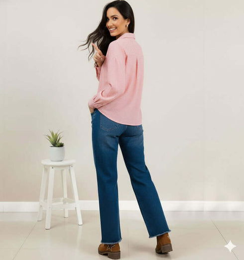 אישה מחייכת עם ג'ינס כחול בגזרה גבוהה וחולצה ורודה, פוזה מצדד.