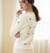 סריג קרדיגן לבן מנוקד בשחור, כפתורים לבנים ותחרה לבנה בחזה ובשוליים, מראה אלגנטי ונעים.