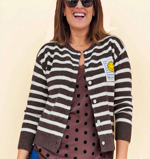 קרדיגן סריג צמר פסים בניגודים חום ושמנת עם פץ' סמיילי צהוב, מראה קלאסי ונינוח.