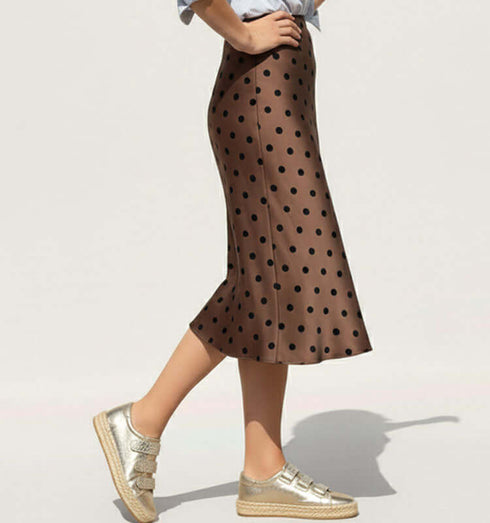 חצאית סאטן מנוקדת טרנדית בגוון חום עם נקודות, ארוכה עד הברכיים, בשילוב עם סניקרס כסף.