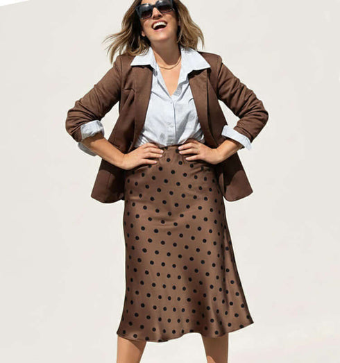 אישה בשמש עם חצאית סאטן מנוקדת בגוון חום, לוק אלגנטי עם סגנון אופנתי, משדרת נוחות ורכות.