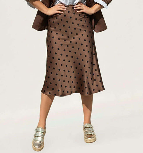 חצאית סאטן מנוקדת טרנדית בגוון חום, ארוכה עד הברכיים עם נעלי ספורט מעוטרות.