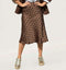 חצאית סאטן מנוקדת טרנדית בגוון חום, ארוכה עד הברכיים עם נעלי ספורט מעוטרות.