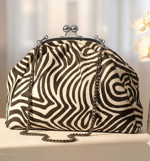 קלאץ' עור ז'אמש עם דוגמת זברה בגוון שחור ולבן, בעל רצועת מתכת לאירועים חגיגיים.