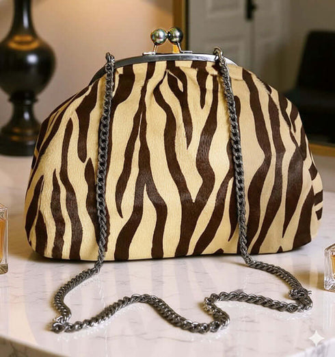 קלאץ' עור ז'אמש בגוון מנומר, עם סגר מתכת ורצועה כסופים, מראה יוקרתי ומודרני.