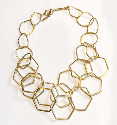 שרשרת זהב מודרנית נוצצת של משושים מחוברים, בסגנון גאומטרי ועשירה עם ברק עדין, מתאימה לבגדי ערב.