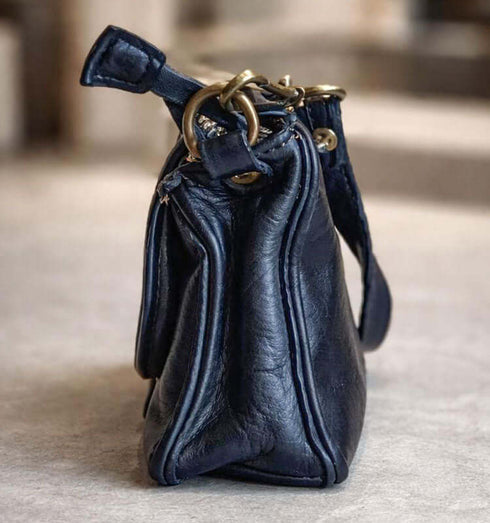 תיק עור בצבע כחול כהה, מעוצב בצורה קומפקטית עם פרטים ייחודיים ואיכותיים.