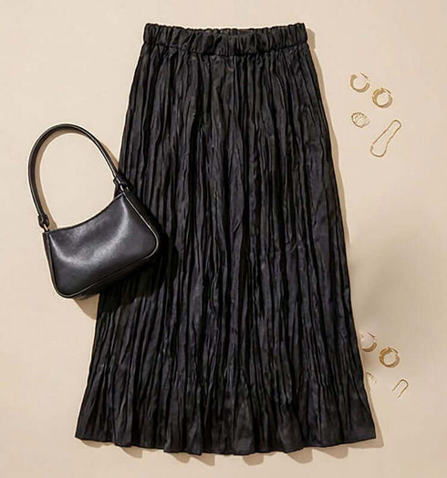 חצאית סאטן משי שחורה עם קימוטים, נראית א-סימטרית ומושלמת לשילוב עם פרטי הלבשה שונים.