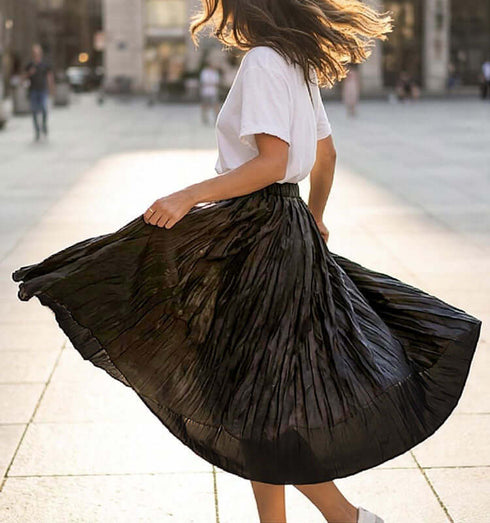 חצאית סאטן בתנועת סיבוב, עם קימוטים שחורים, משולבת עם חולצת טי לבנה, בסטייל אלגנטי.