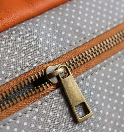 תיק צד מעור נפה בגווני תכלת, כתום עם רצועת כתף סגולה, דגש על רוכסן עם בד מנוקד.