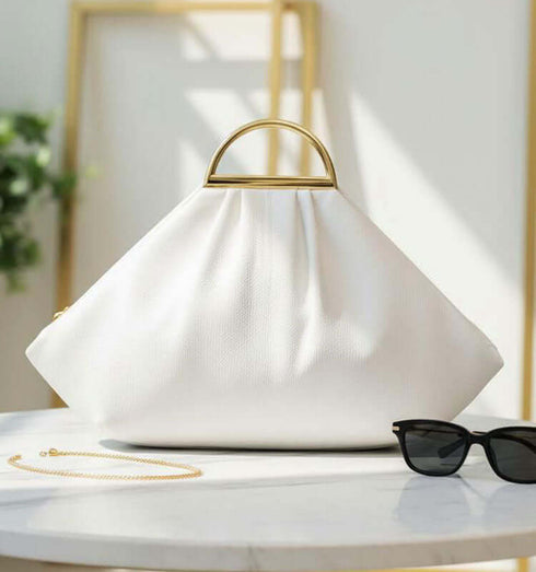 תיק ייחודי מעור איטלקי בגוון לבן עם ידיות מוזהבות, מראה יוקרתי, רצועה תואמת לנשיאה.